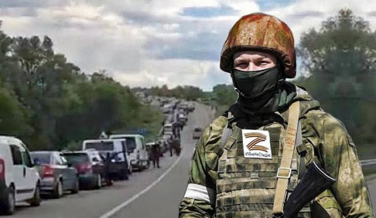 Російський військовий на фоні автомобільної черги