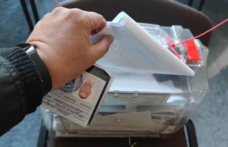 Людина опускає бюлетень в скриньку для голосування