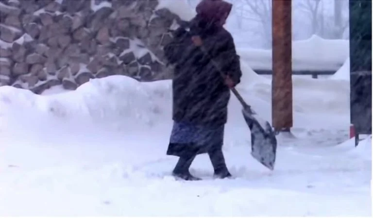 Жінка з лопатою прибирає сніг