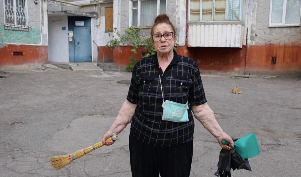 Літня жінка з віником і совком