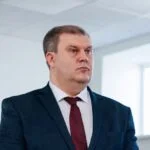 Чоловік у темному костюмі стоїть у приміщенні