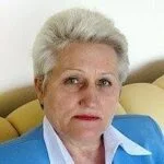 Жінка з коротким сивим волоссям у блакитному піджаку
