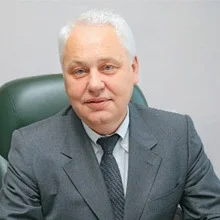 Чоловік у сірому костюмі сидить у кріслі