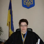 Суддя у мантії на тлі прапора та герба України