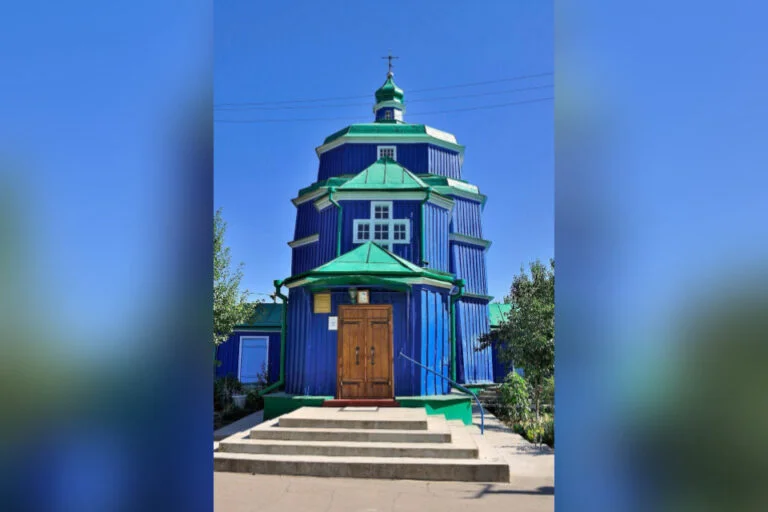 Синя дерев’яна церква із зеленим дахом і хрестом