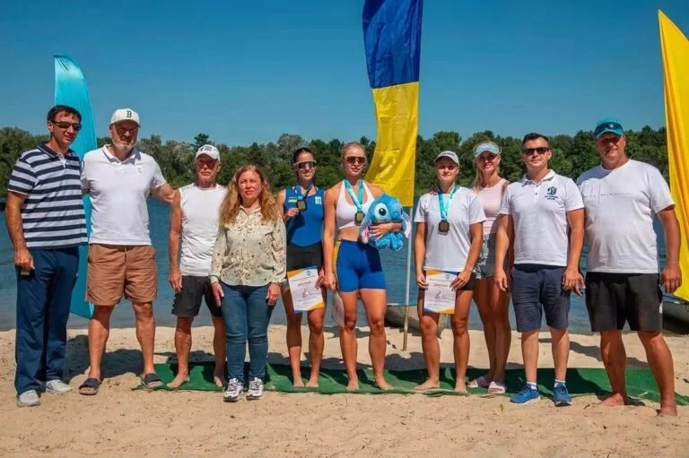 Група веслувальників із медалями та дипломами на пляжі