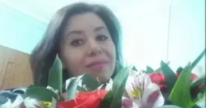 Жінка позує з букетом квітів у приміщенні