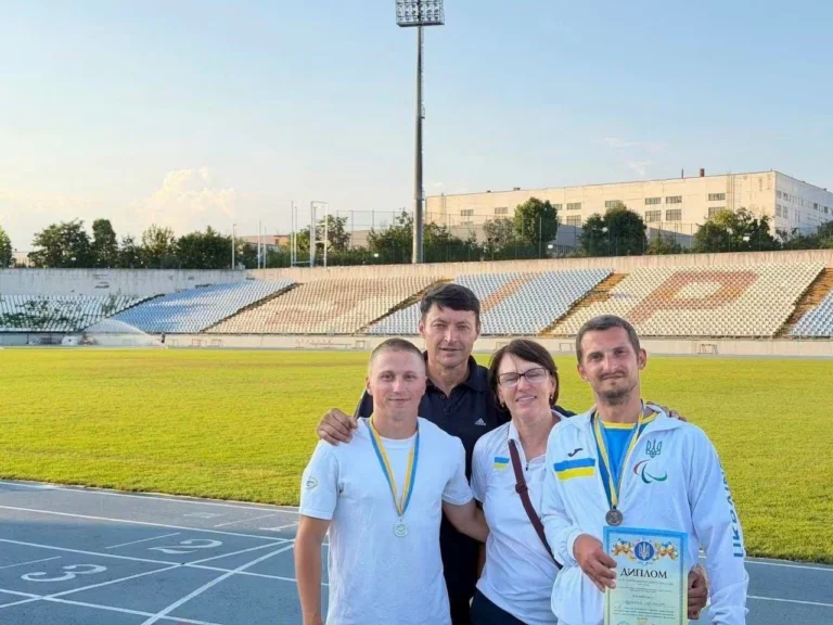 Четверо людей з медалями на легкоатлетичному стадіоні