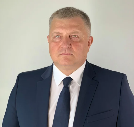 Чоловік у темному костюмі та краватці на світлому фоні