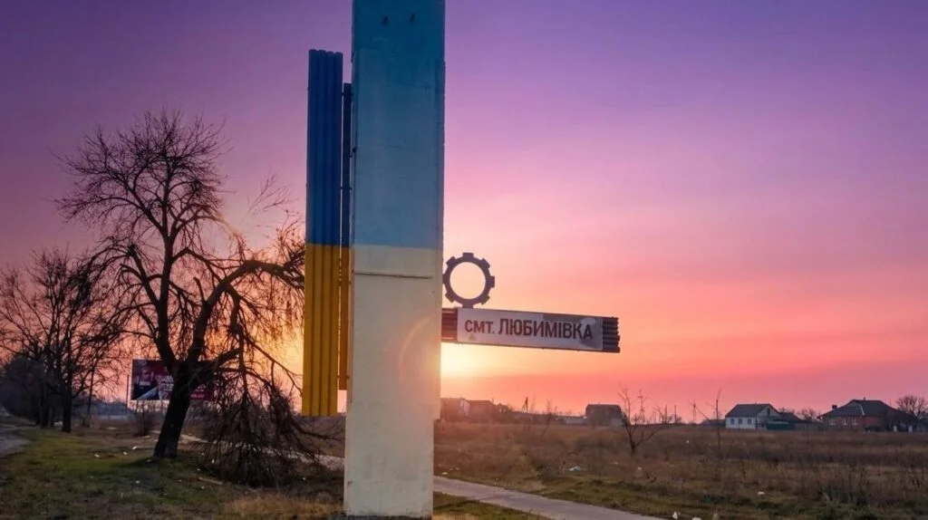 Стела з написом смт Любимівка на тлі заходу сонця
