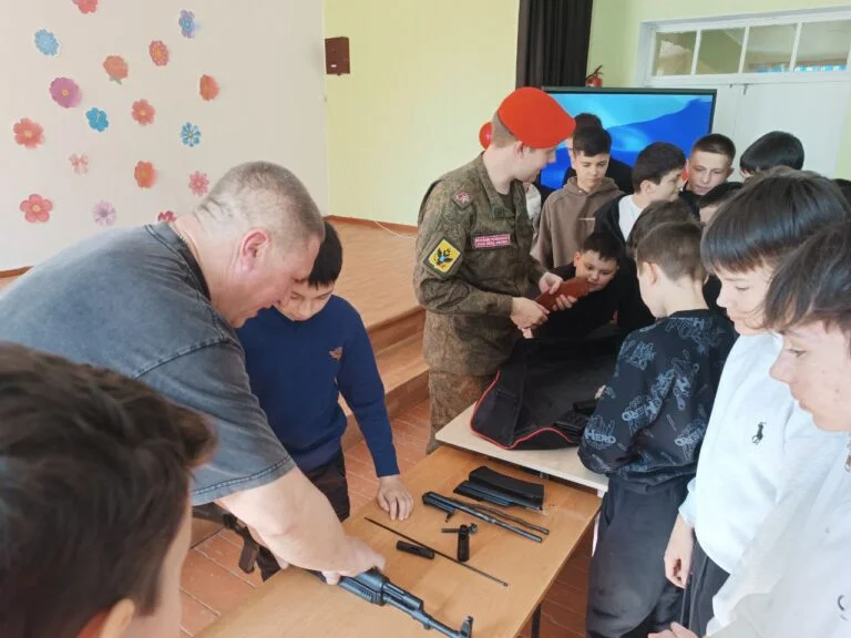 Дорослі демонструють зброю групі дітей у приміщенні