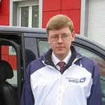 Чоловік у куртці стоїть біля відчиненого автомобіля