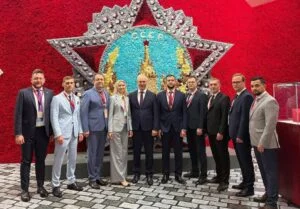 Група людей у костюмах на тлі радянської символіки